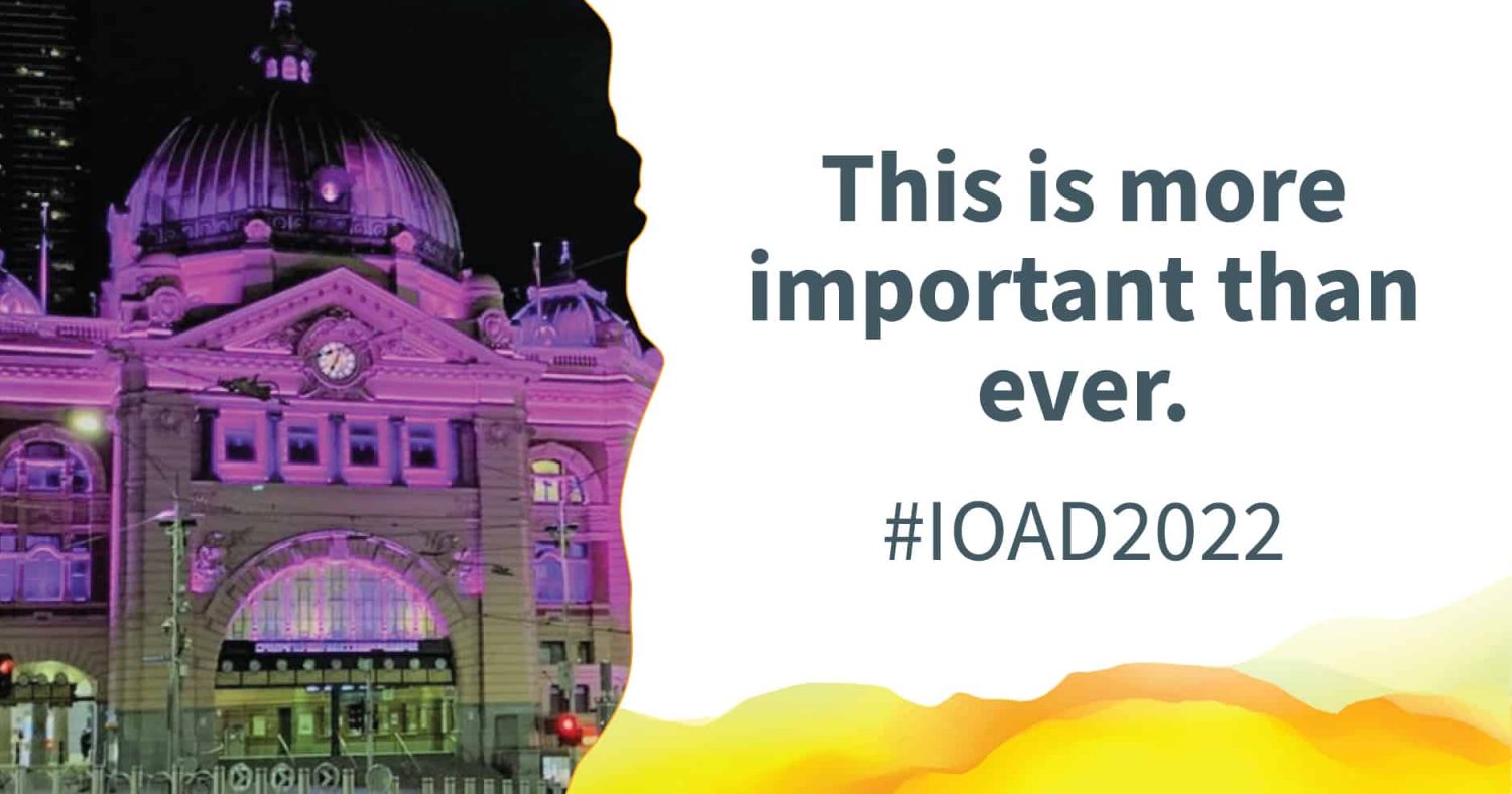 Flinders Street Station lit up with purple light. Text alongside reads: "This is more important than ever. #IOAD2022"