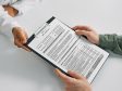 Image of clipboard with ASSIST alcohol and drug screening tool on it being handed by doctor to patient