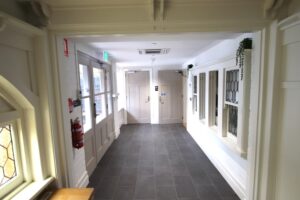 A corridor with large entry door at left, reception window at right, and accessible bathrooms at the end