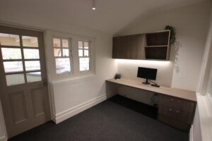 A medium sized room with a desk and cabinet at one end with phone and computer