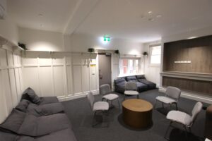 A large room with chairs around a small round table in the centre, flanked by recliners